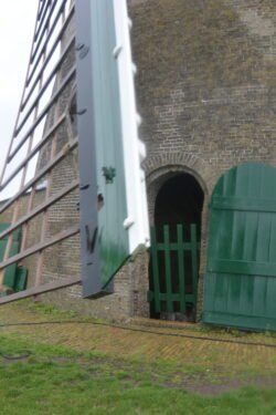 windmill sail passing an arched doorway into the windmill base