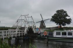 small pedestrian drawbridge with canal boat and windmill