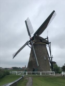 a large dutch windmill with body of stone, and four large sails on a rotating upper structure