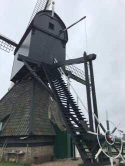 large dutch windmill with a shingled lower section and a hut-shaped rotating upper section.